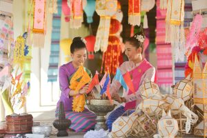 Two women in their traditional thai outfit sitting on floor surr