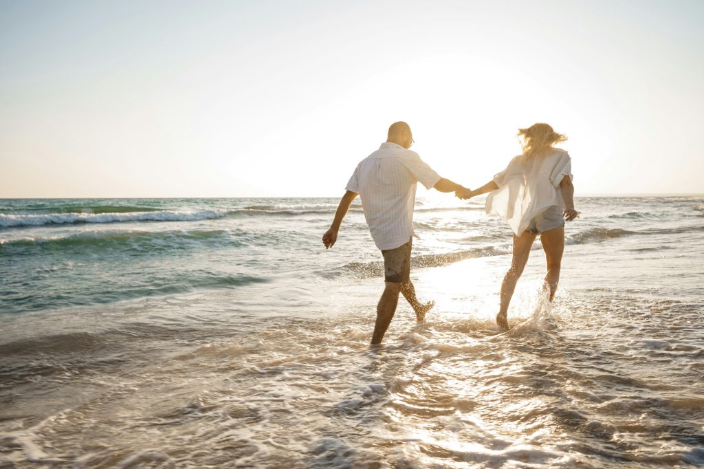 Young beautiful couple walking on beach near sea